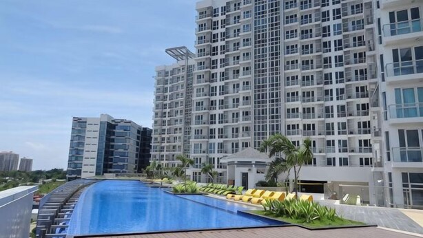 A swimming pool with a wooden deck, surrounded by modern high-rise buildings.