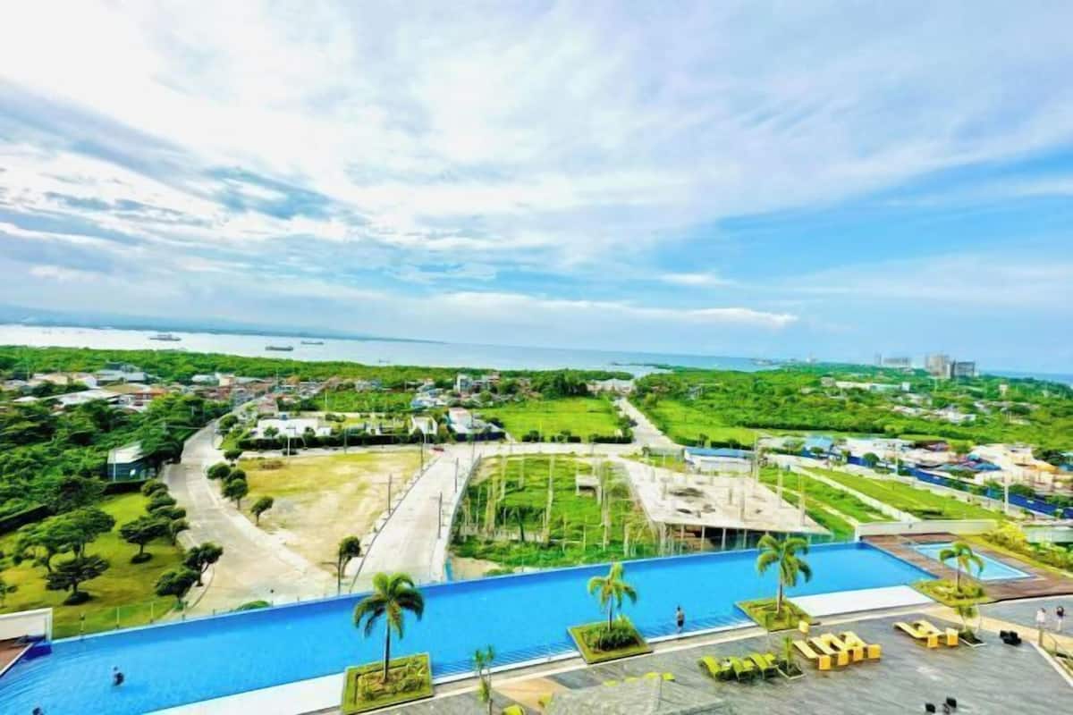 A resort with a large swimming pool, palm trees, and a view of the ocean.