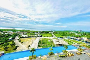 Un resort con una amplia piscina, palmeras y vista al océano.