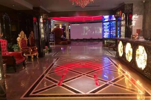A lobby with a geometric patterned floor, a reception area with a digital display, and ornate red seating. - Friendly Hotel (Meimei Shopping Center Autonomous Region Museum Branch) (Urumqi)