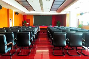 Een congreszaal met rijen stoelen gericht op een podium.