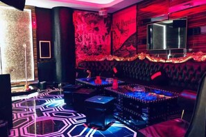 Una zona de bar con piso estampado, una barra y una pantalla de televisión.