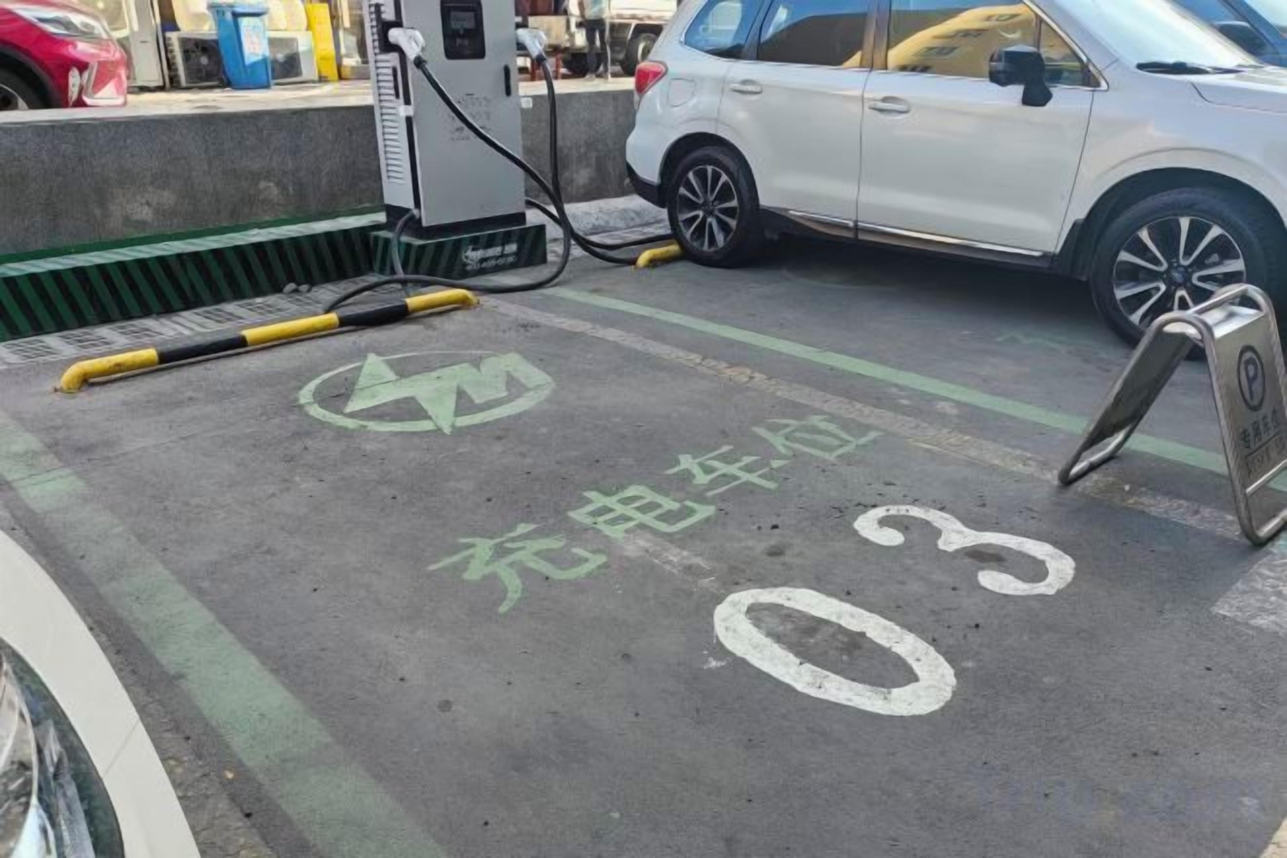 A parking area with a charging station, a white car, and a designated parking space marked with the number 03.