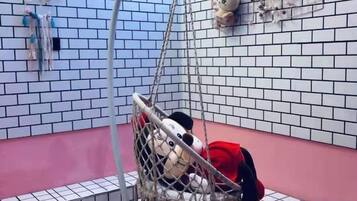 A room with a hanging chair, a pink wall, and a brick-patterned wall.