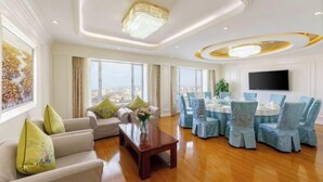 A spacious living area with a wooden floor, a sofa set, a dining table with chairs, and a large window offering a city view. - Friendly Hotel (Meimei Shopping Center Autonomous Region Museum Branch) (Urumqi)