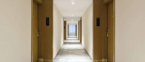A long, narrow hotel corridor with wooden doors on either side and a tiled floor.