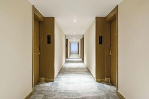 A long, narrow hotel corridor with wooden doors on either side and a tiled floor. - Friendly Hotel (Meimei Shopping Center Autonomous Region Museum Branch) (Urumqi)