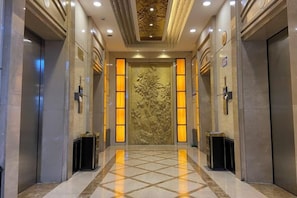 A hotel lobby with a marble floor, a large ornate door, and two elevators. - Friendly Hotel (Meimei Shopping Center Autonomous Region Museum Branch) (Urumqi)