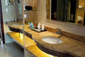 A bathroom with two sinks, a large mirror, and a shelf with toiletries.