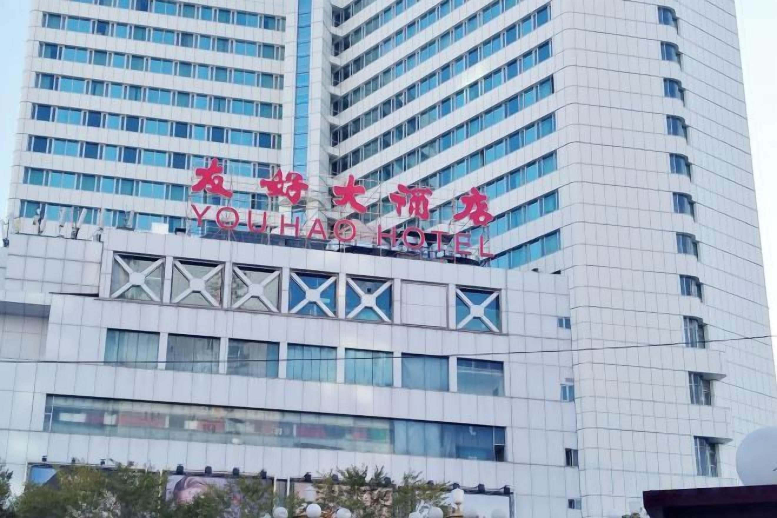 A hotel building with a modern design, featuring a prominent sign with Chinese characters and the name 'YouHao Hotel' in English.