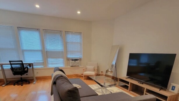 Un salon moderne avec un grand canapé, un téléviseur à écran plat et un bureau avec une chaise.