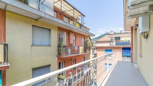 Un immeuble résidentiel à plusieurs étages, doté de balcons, d’une allée dallée et surplombant un ciel dégagé.
