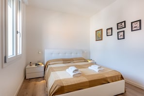 Una camera d'albergo con un letto, comodini, una finestra e decorazioni alle pareti.