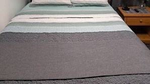 A neatly made bed with patterned bedding, a bedside table with a lamp, and two floral wall art pieces. - Fun Home w/AC and TVs  In All/Pool Nearby/BBQ Grill/Firpit/Games/Amenities/
 (Tobyhanna)