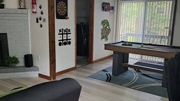 A living room with a pool table, a dartboard, and a fireplace.