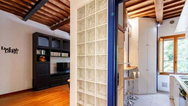 Una cocina moderna con armarios blancos, horno empotrado y ventana que proporciona luz natural.
