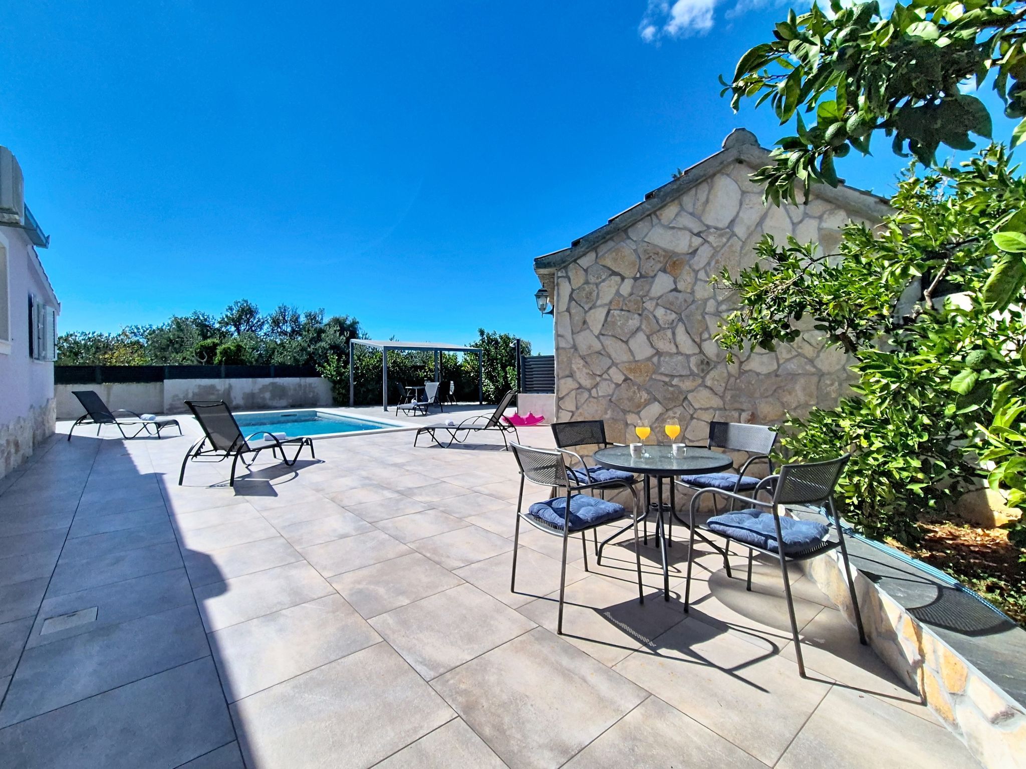 A patio area with a pool, outdoor seating, and a stone wall.