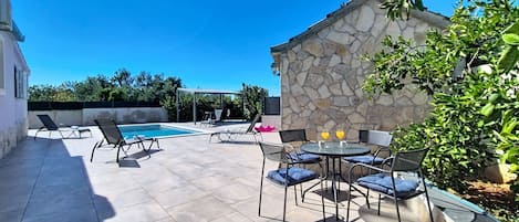 A patio area with a pool, outdoor seating, and a stone wall.