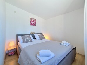Un lit bien fait, avec des oreillers, une lampe de chevet et des serviettes posées sur le sol.
