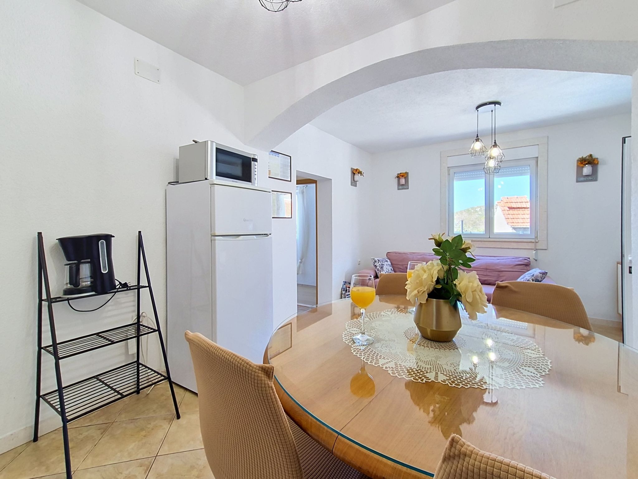 A modern kitchen with a dining table, chairs, a coffee machine, and a refrigerator.