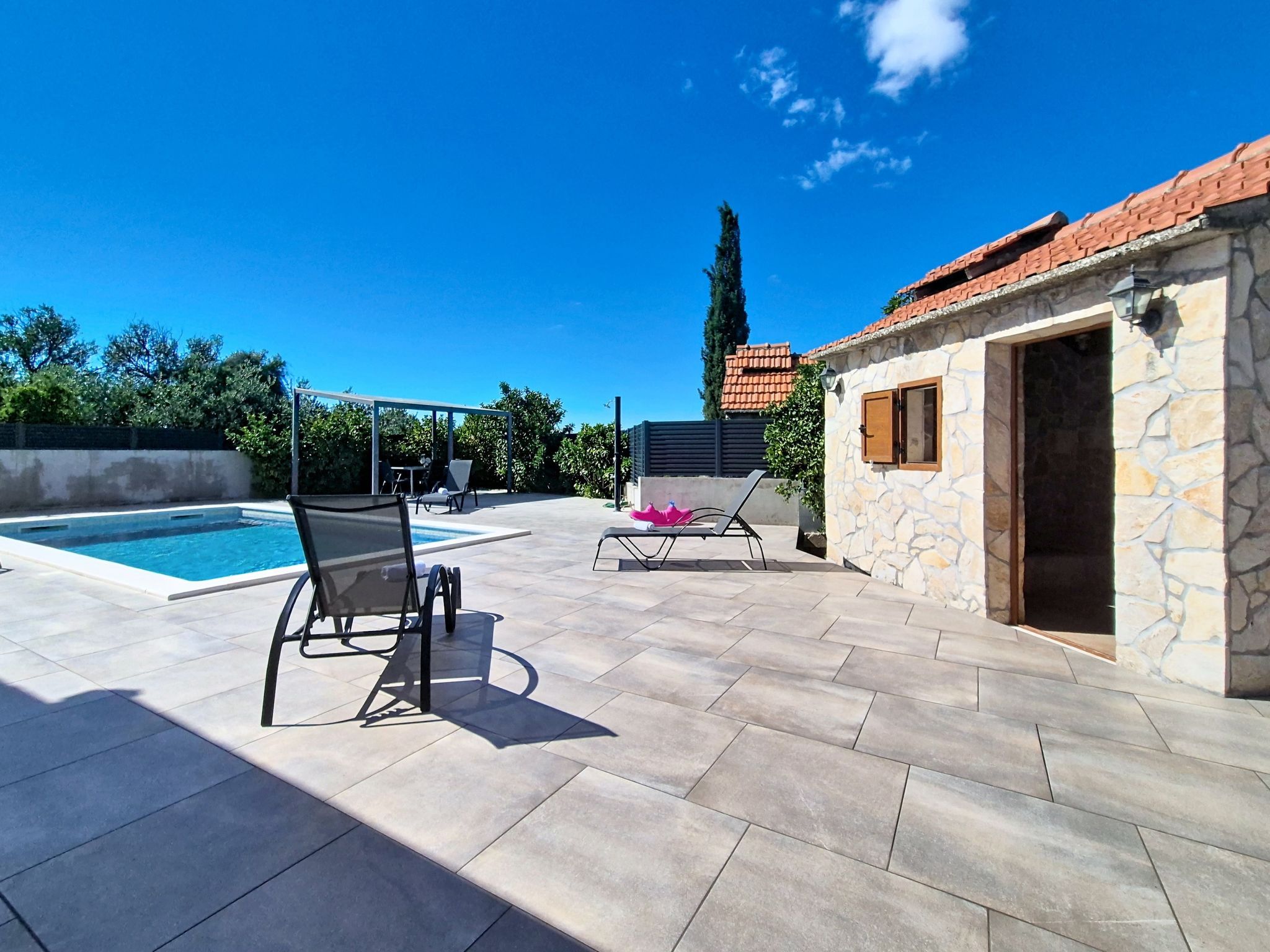 A pool area with lounge chairs and a covered seating area.