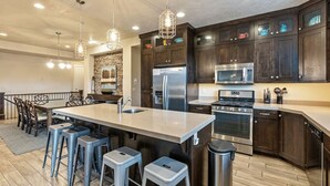 Una cocina moderna con armarios de madera oscura, electrodomésticos de acero inoxidable y una isla central con taburetes de bar.