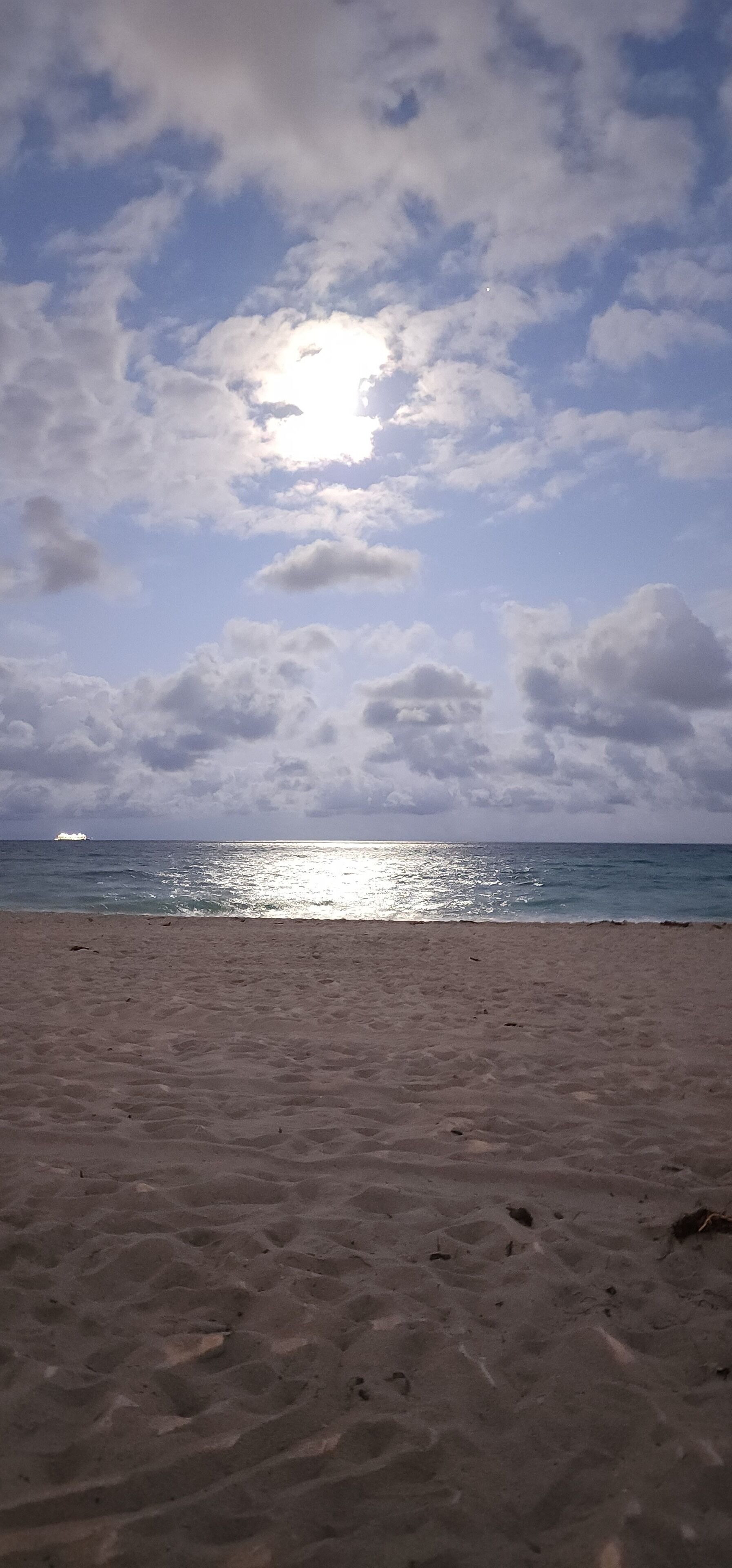 A beach with a clear sky and sunlight reflecting on the water.