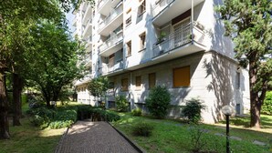 A multi-story residential building with balconies, a paved pathway, and surrounding greenery. - GuestHost - Cà Granda M5 & Bicocca - Apartment Cosy (Milano)