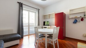 A compact living space with a dining area, a sofa, a TV, and a red cabinet. - GuestHost - Cà Granda M5 & Bicocca - Apartment Cosy (Milano)