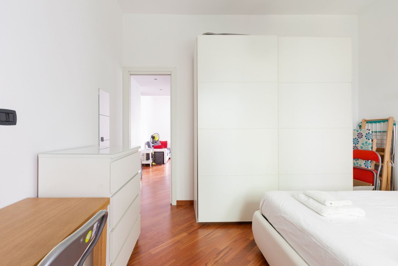 Un dormitorio con cama, cómoda, armario y escritorio.