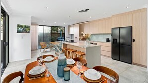 Une cuisine moderne dotée d’un grand réfrigérateur, de meubles en bois et d’un coin repas avec une table dressée pour quatre personnes.