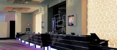 A modern hotel lobby with a reception desk, a patterned wall, and a carpeted floor.