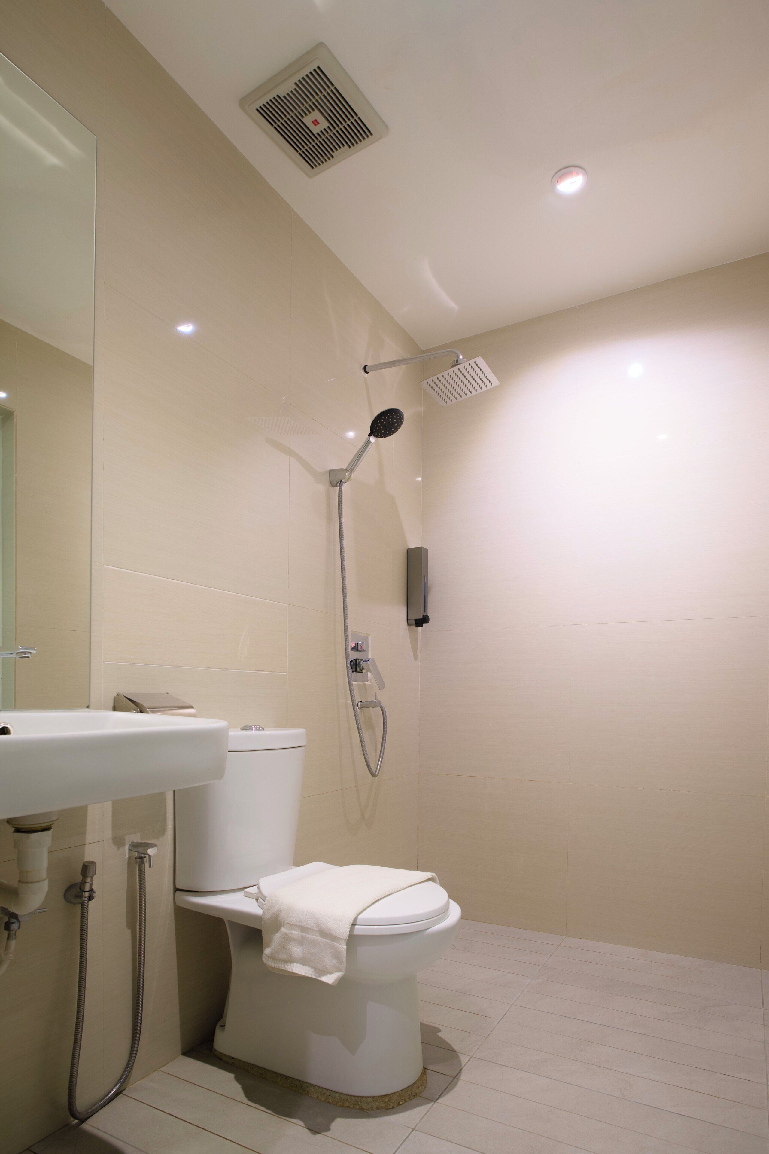A modern bathroom with a toilet, shower, and sink.