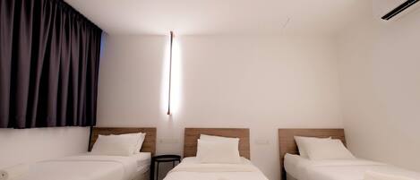 Una habitación de hotel con dos camas individuales, una mesita pequeña y un aire acondicionado instalado en la pared.