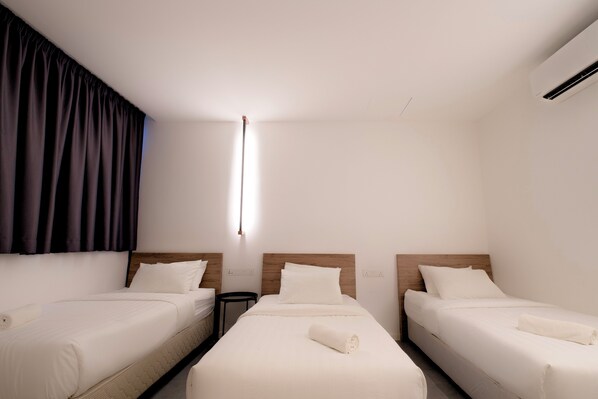 Hotellihuone, jossa on kaksi erillistä sänkyä, pieni pöytä ja seinälle asennettu ilmastointilaite.