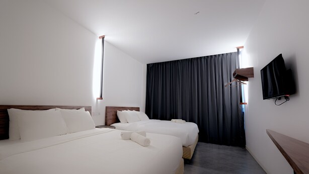 A hotel room with two beds, a flat-screen TV mounted on the wall, and a large window with curtains. - T Hotel Jalan Sultanah (Alor Setar)