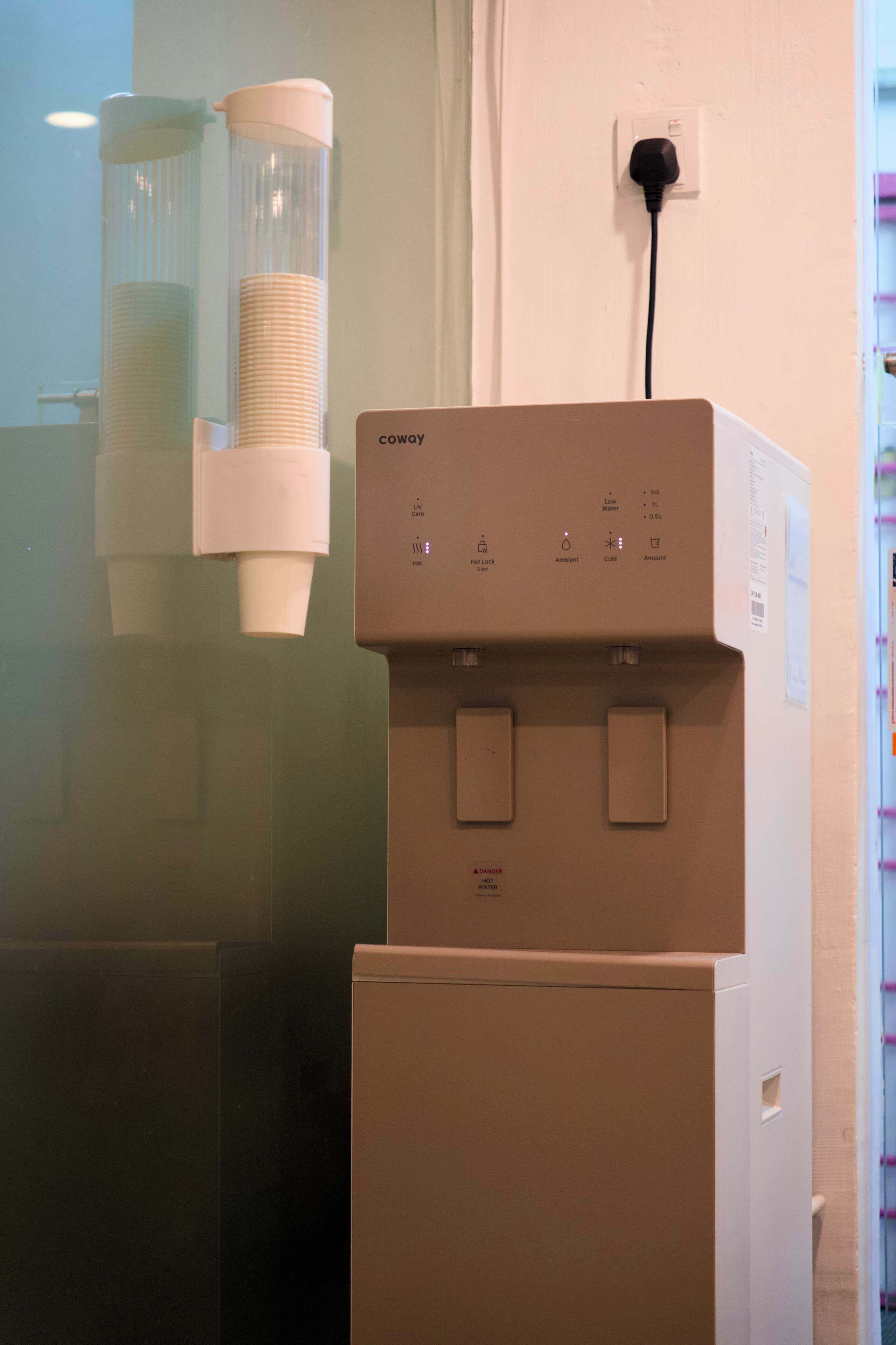 A water dispenser with a control panel and a glass container.