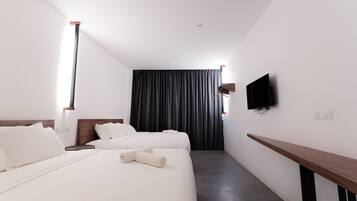 A hotel room with two beds, a flat-screen TV mounted on the wall, and a wooden bench.