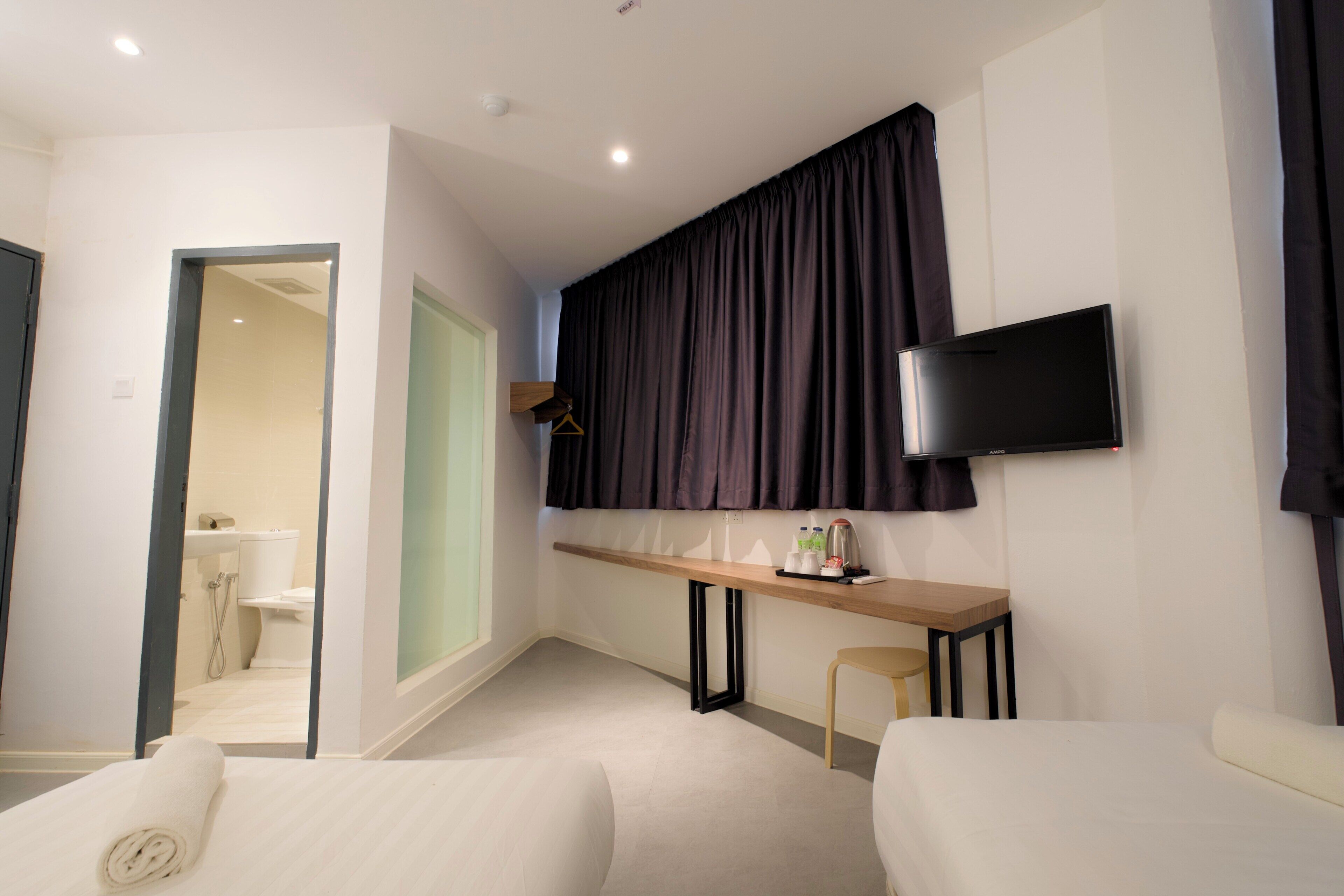 Une chambre d’hôtel avec un lit, un bureau, une télévision et une vue sur la salle de bain.