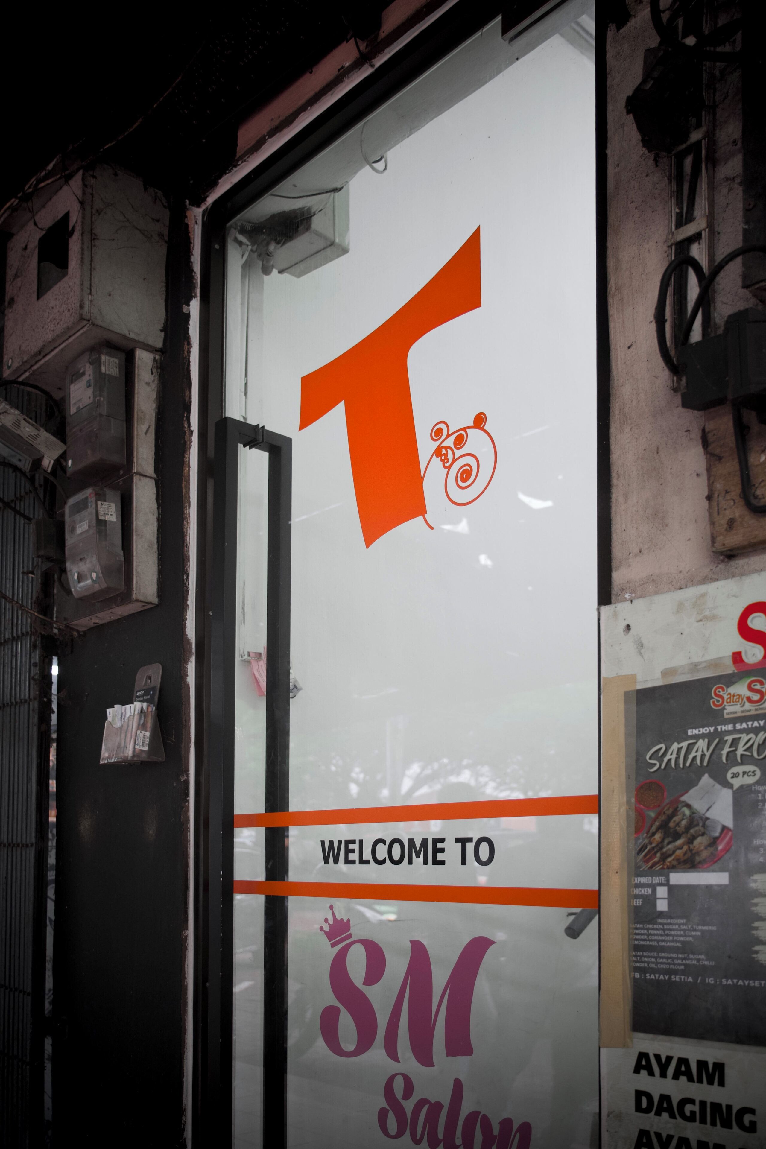 A storefront with a large glass window displaying the logo 'T' and the text 'WELCOME TO SM Salon'.
