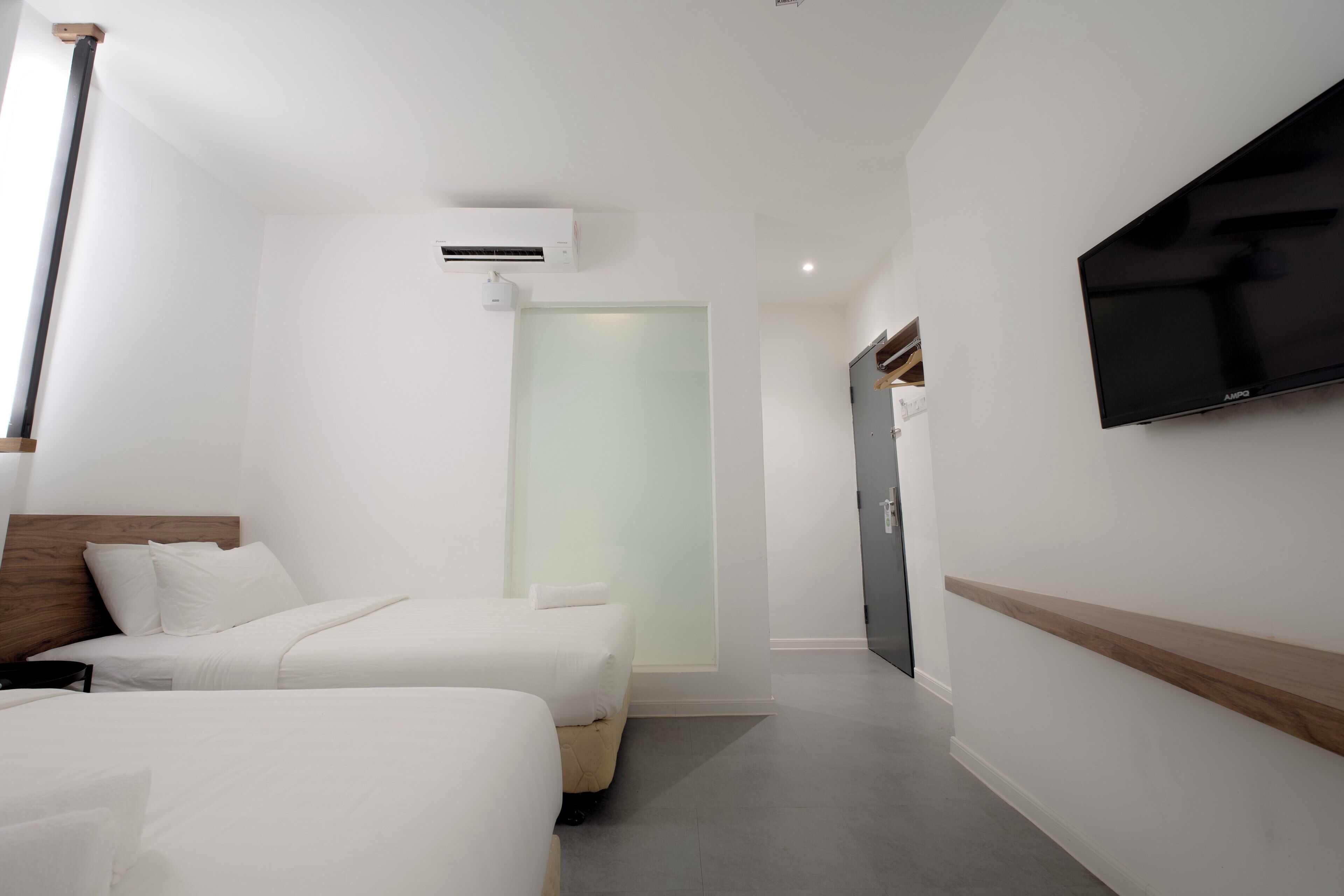 A hotel room with two beds, a TV, and a sliding door leading to a bathroom.