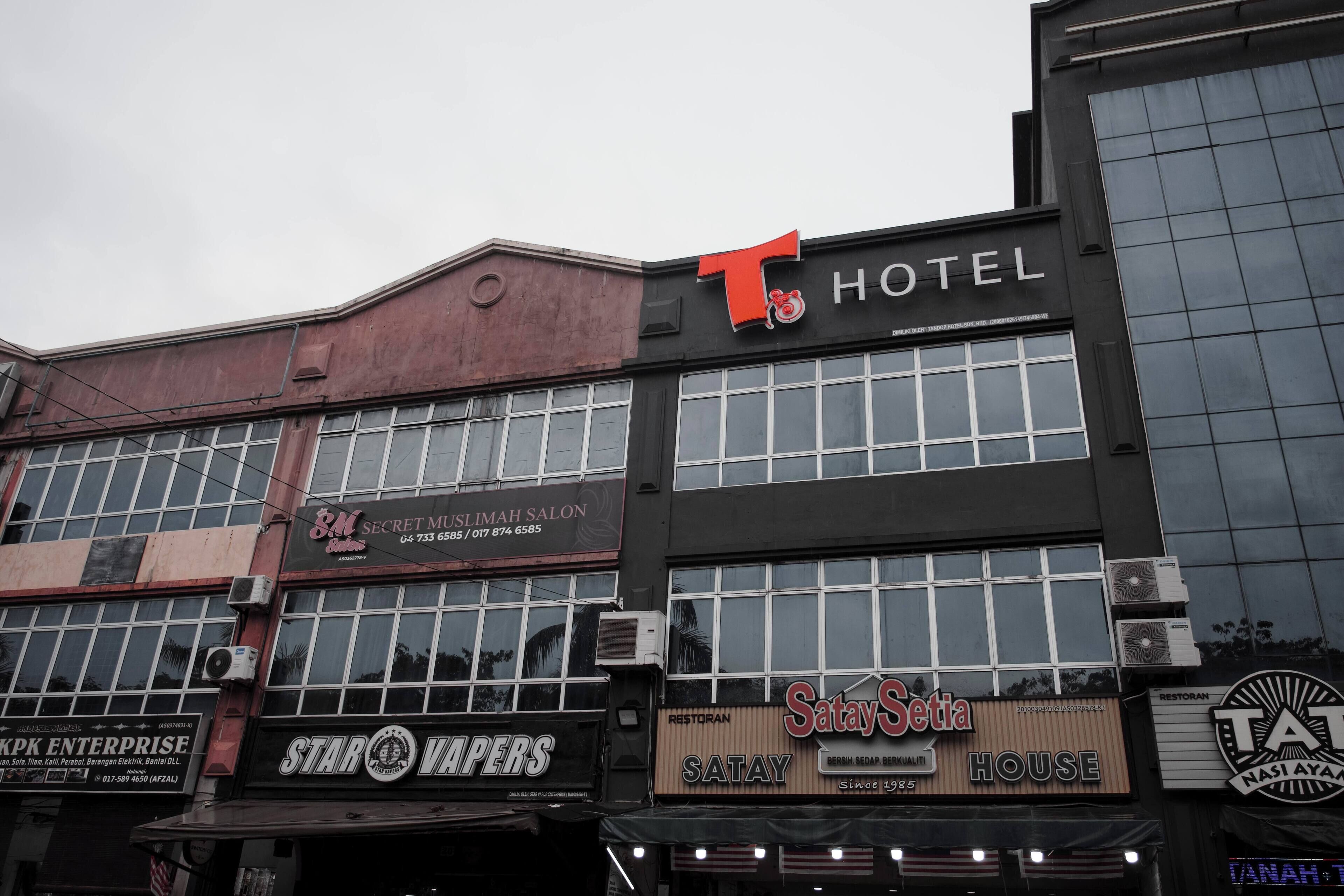 A hotel with a prominent 'T' sign, multiple storefronts including 'Star Vapers' and 'Satay Setia', and a 'Restoran Satay' sign.