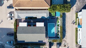 Vista aérea de un edificio con piscina, cancha de tenis y aparcamiento.