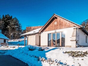 Una casa moderna de madera con puertas de cristal grandes y un cimiento de piedra.