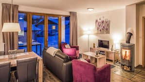 A cozy living room with a sofa, chairs, a TV, a fireplace, and a dining area with a table and chairs. - Residence Lipno by Interhome (Lipno nad Vltavou)
