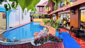 An indoor swimming pool with a tiled edge, surrounded by plants and a bench. - Rosetta Hotel (Phu Quoc)