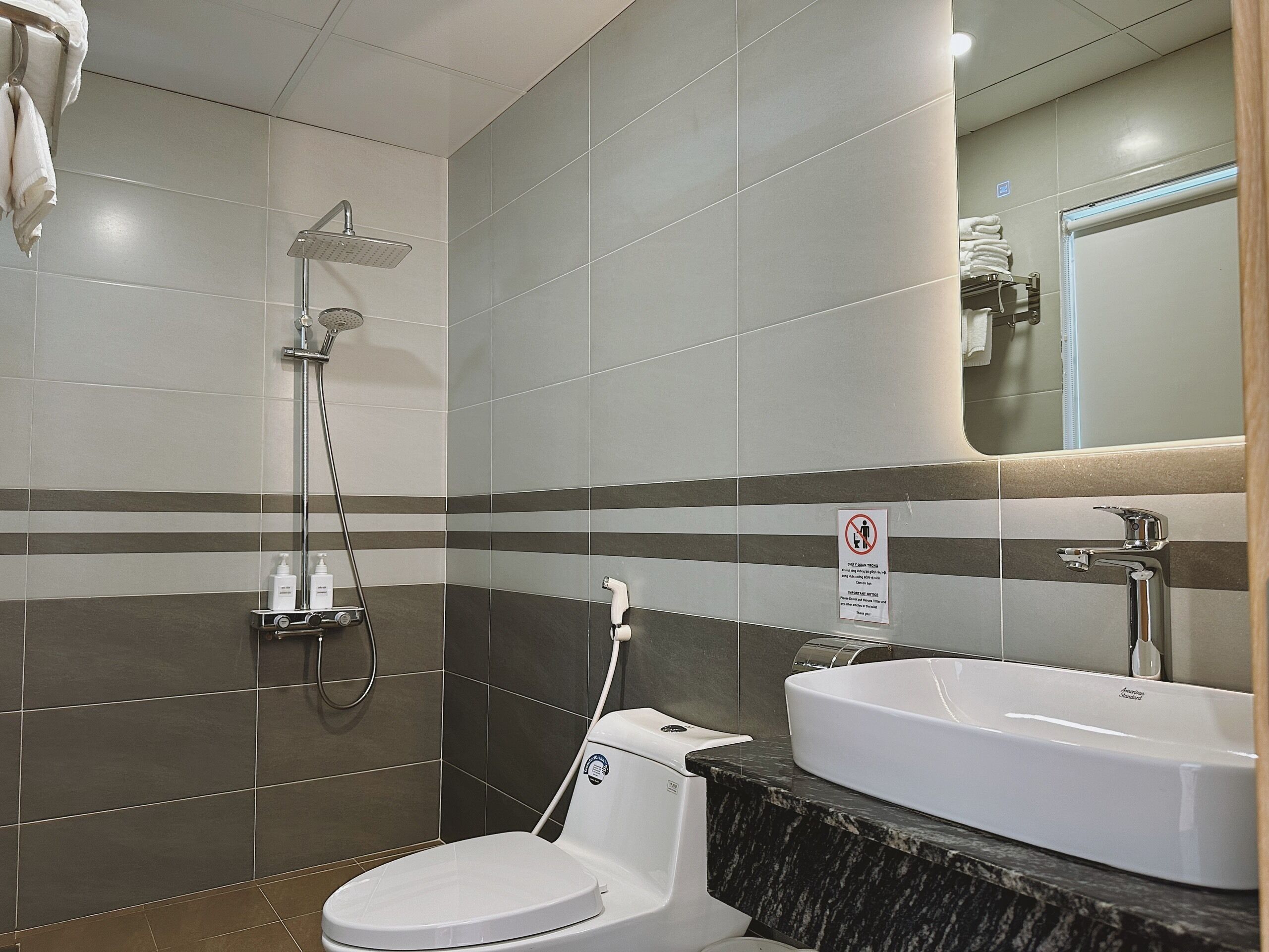 Een moderne badkamer met douche, toilet en wastafel.