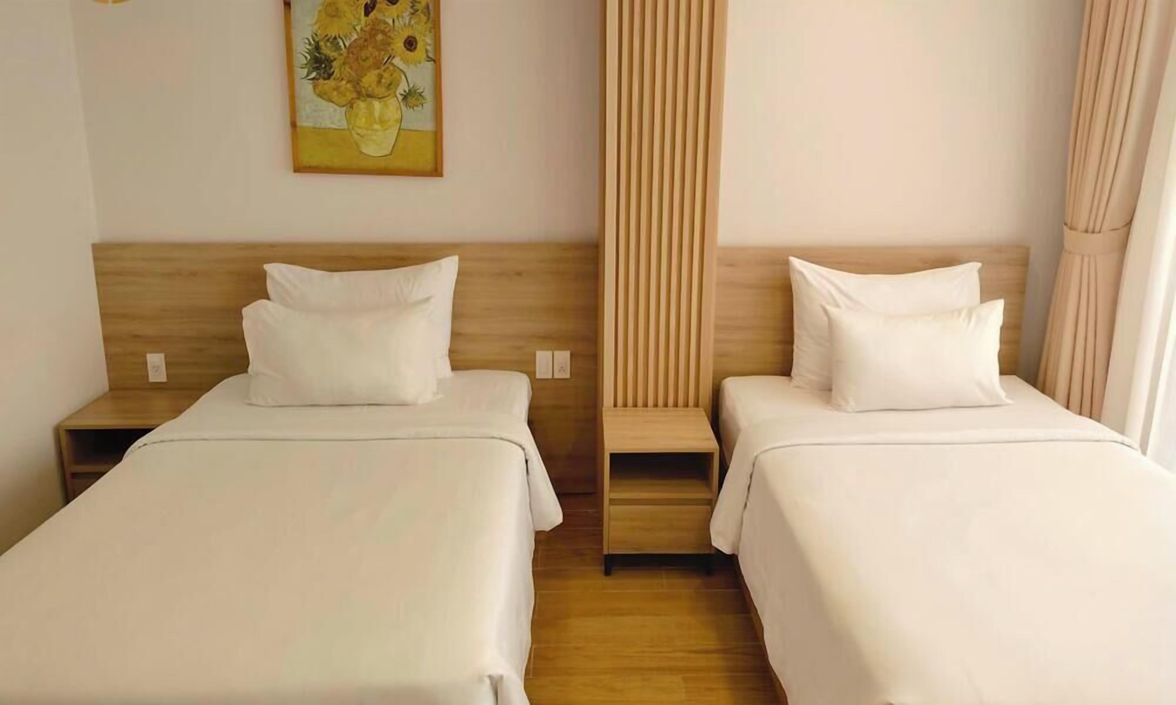 A hotel room with two single beds, wooden headboards, and a painting on the wall.