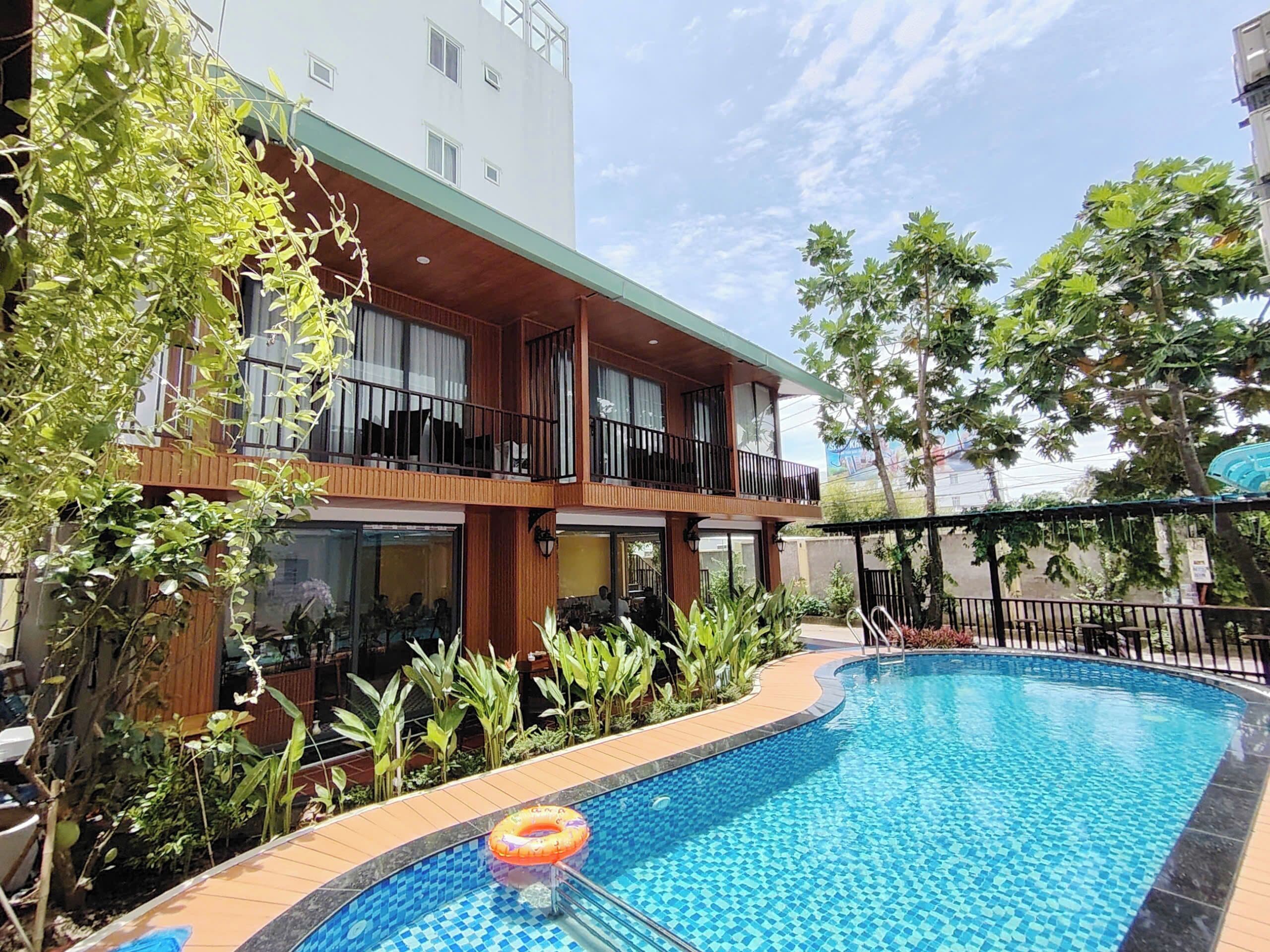 Un hotel con piscina, balcones de madera y abundante vegetación.