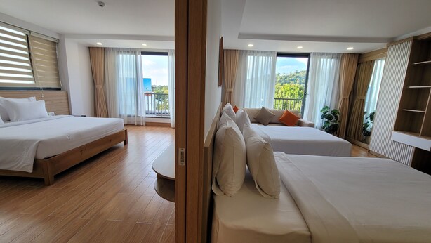 A hotel room with two beds, a balcony with a view, and a wooden floor. - Rosetta Hotel (Phu Quoc)